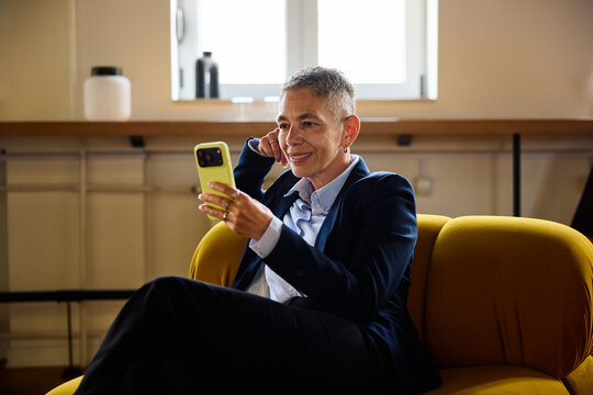 Ederly woman sits in a corporate lobby, using her smartphone