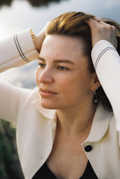 A woman runs her hand through her hair in contemplative moment