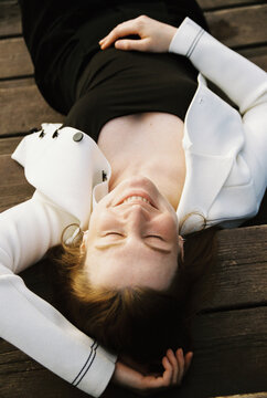 A woman lies in warm sunlight on weathered wooden decking