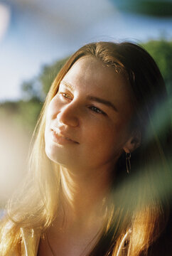A young woman smiles softly in warm afternoon light