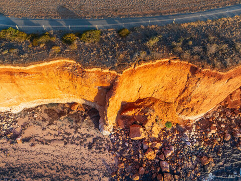 Vertical cliff faces above a rocky coastline in golden morning light
