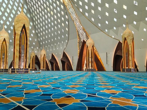 Bandung, Indonesia - July 08, 2026: Architectural beauty of the grand Al Jabbar Grand Mosque interior featuring rows of ornamented pillars and patterned blue gold carpet.