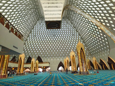 Bandung City, Indonesia - July 08, 2026: The atmosphere of worship and congregation visits inside the main hall of Al-Jabbar Grand Mosque featuring futuristic latticed roof.