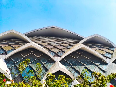 Bandung, Indonesia - July 08, 2026: Grand architecture of Al Jabbar Grand Mosque featuring geometric glass facade and modern curved roof structure under clear blue sky.