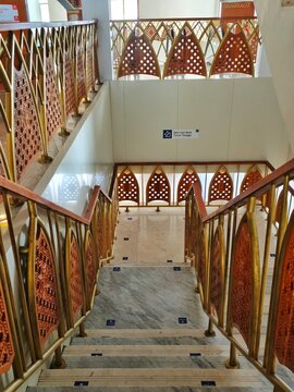 Bandung, Indonesia - July 08, 2026: Interior stairs of Al Jabbar Grand Mosque with gray marble floors and wooden carved stair railings with distinctive geometric gold ornaments.