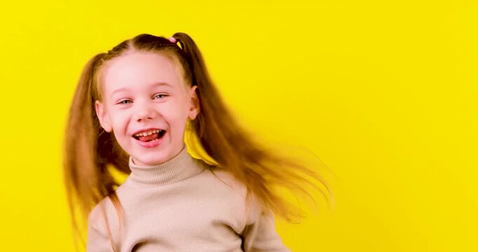 Video of a playful young girl on a yellow background rubbing her eyes before making a funny face and sticking out her tongue. Concept of childhood, emotions, humor, playfulness, and facial expressions