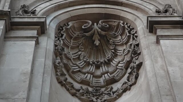 Low angle view revealing an intricate rococo or baroque style stone carving on a historic building. Detailed architectural relief on a church facade