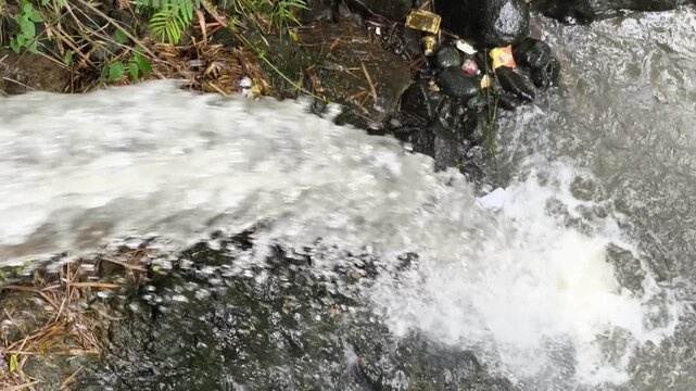 The fast movement of a clear river water stream passing over rocks creating clean white ripples and foam.