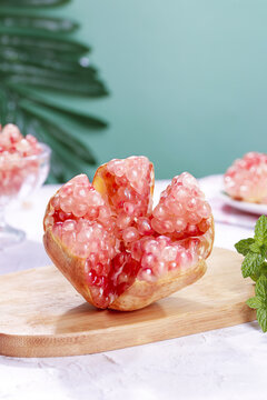 Fresh Pomegranate Seeds and Arils on Wooden Board with Tropical Leaves - Healthy Antioxidant Fruit