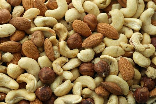 Detailed view on almond and cashew nuts in big pile on table close up