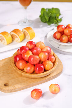 Fresh Golden Chilean Cherries in Wooden Bowl with Elegant Food Display on White Marble Table