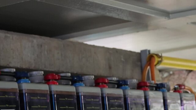 Panning right video of red and blue industrial backup battery bank terminals  medium voltage container switchgear control system.