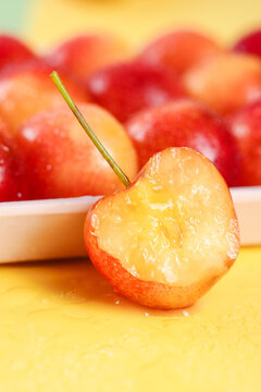 Fresh Cut Rainier Cherry with Golden Flesh and Stem Against Red Cherry Background