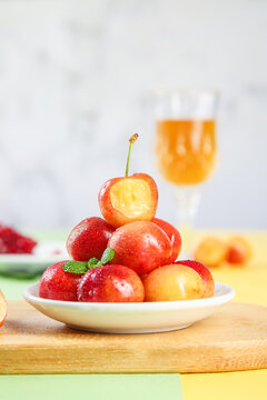 Fresh Gold Chilean Rainier Cherries with Mint on White Plate and Orange Juice Background