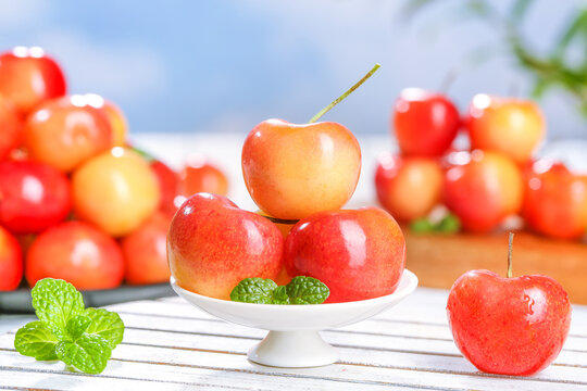 Fresh Golden Yellow Rainier Cherries from Chile on White Pedestal with Mint Garnish