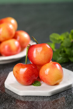 Fresh Golden Yellow Rainier Cherries from Chile on White Plate with Mint Garnish