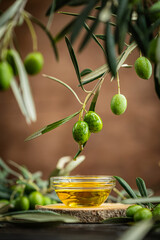 Naklejka premium Small glass bowl filled with olive oil placed on wooden surface surrounded by fresh green olives and olive branches. Concept of Mediterranean cuisine, organic farming, healthy food and natural harvest