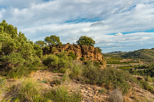 Wild Mediterranean scrubland frames a sandstone cliff above the fertile Turia valley. Ideal for rural travel, ecotourism, and Spanish countryside editorial projects seeking untamed natural.