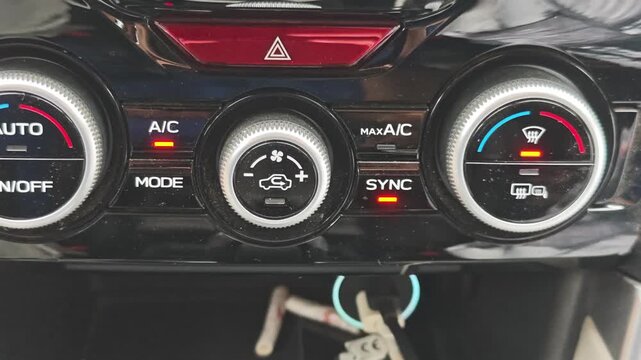 Close up of a red hazard warning light button blinking on a car's climate control panel. Driver activating the emergency signal