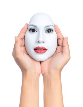 A white mask with red lips and eye makeup held by two hands on a white background