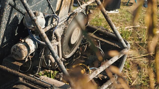 A close-up of a dirty off-road buggy with a rotating cooling fan. Mud splashes onto the mechanical parts during an off-road racing competition. Concept of extreme motorsports in natural daylight