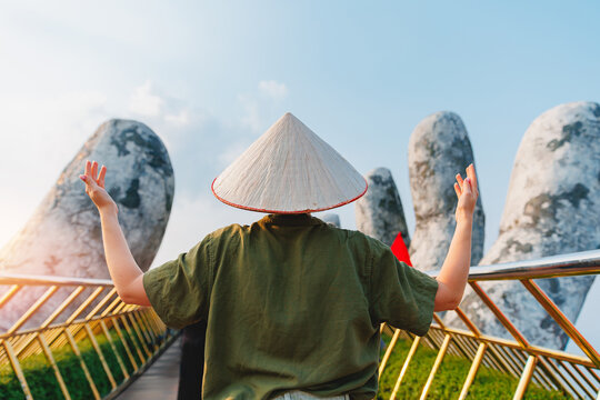 Golden bridge in ba na hills, Da nang, tourist with conical hat embracing scenic back view