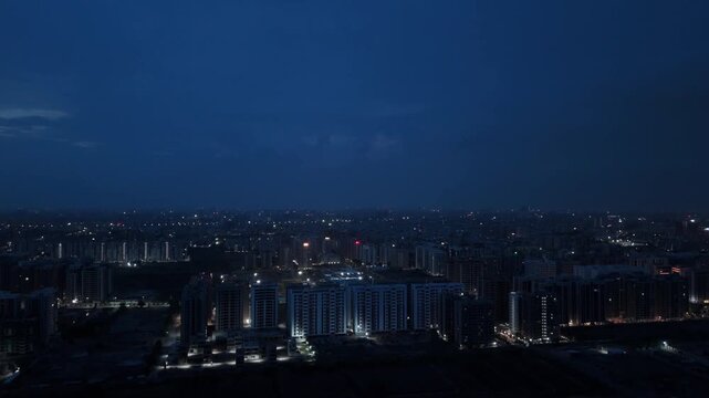 Aerial Drone View of Illuminated Urban Skyline at Blue Hour with High Rise Residential Buildings and City Lights in Surat, Gujarat, India
