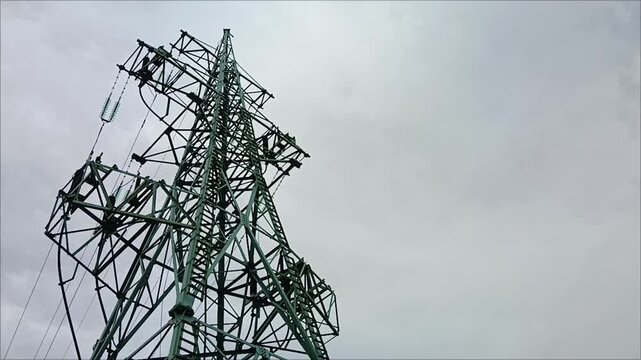 High voltage power line tower against cloudy sky. Electricity transmission pylon, industrial energy infrastructure closeup. Energy crisis concept, electricity shortage, blackout and inflation.