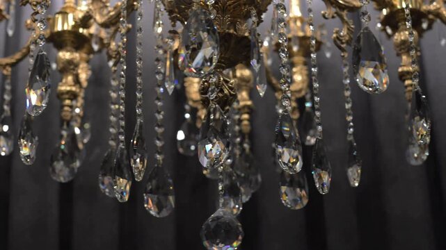 Sparkling crystal chandelier with shimmering reflections on dark fabric background in slow motion. Cinematic slow-motion footage highlighting luxurious vintage design, premium decor, refined craftsman