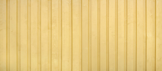 Fototapeta premium Gelb gestrichene Holzwand aus vertikalen ungehobelten Brettern mit rauer Textur, komplett ohne Schrauben