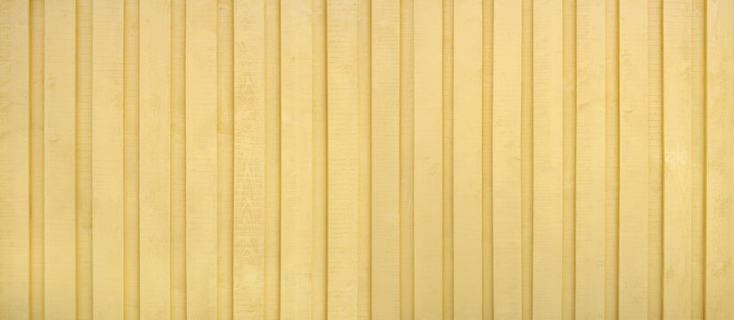 Gelb gestrichene Holzwand aus vertikalen ungehobelten Brettern mit rauer Textur, komplett ohne Schrauben