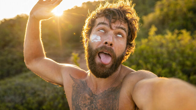 Shirtless bearded man with sunscreen making funny face outdoors