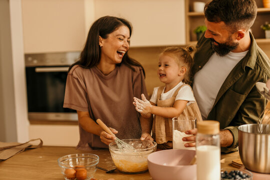 Happy family baking together in kitchen, making cookies
