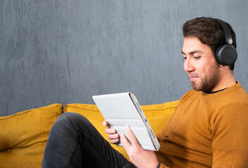 Man using digital tablet while wearing wireless headphones at home © Diego D
