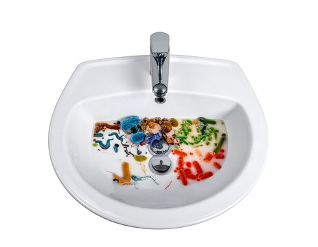 A white porcelain sink with a silver faucet and vibrant paint splatters