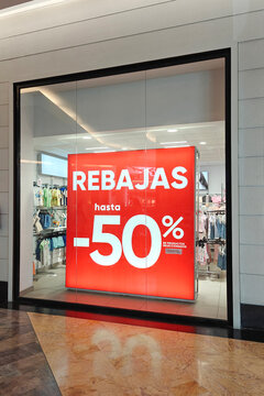 Discount red sign board in store window inside shopping mall. Sale season in Spain