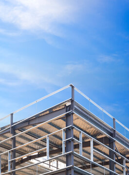 Steel framework of new industrial warehouse building roof structure with insulation panels in construction site under blue sky in vertical frame