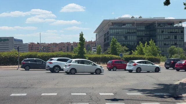 Madrid, Spain, June 30, 2026: Vehicles wait at traffic lights in front of modern office buildings on a clear summer day in Madrid. Editorial use only.