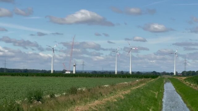 Modern wind turbines in agricultural landscape under blue sky