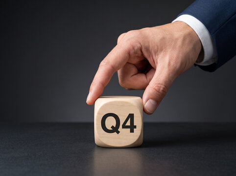 Professional businessman placing premium wooden Q4 cube on executive desk representing fourth quarter business planning and corporate strategy