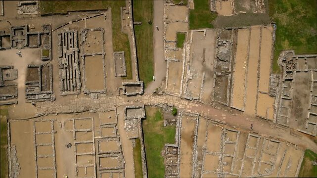 Aerial view tracking visitors exploring the ancient ruins of an archaeological site in Italy