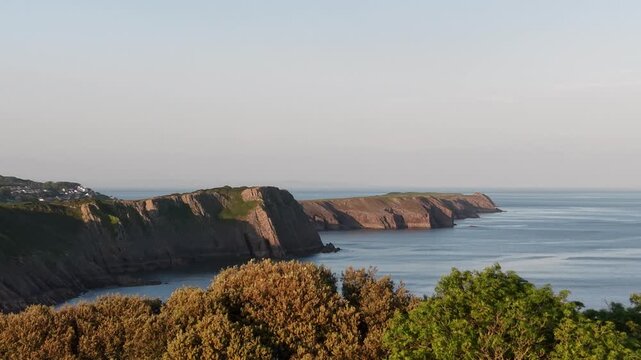 Pembrokeshire Coast Path, Wales - Aerial drone view of dramatic coastal cliffs meeting the calm ocean at sunset