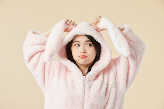 Young woman in pink bunny pajama hoodie making funny pout