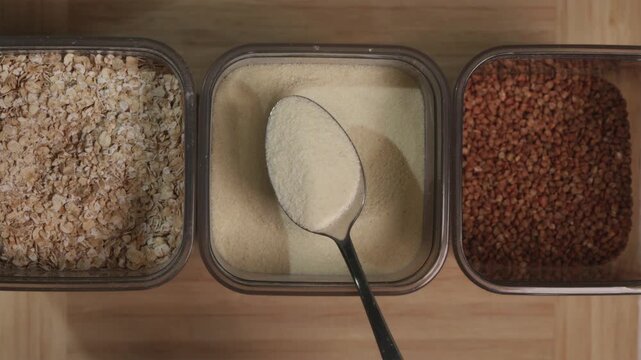 Metal spoon taking a portion of raw semolina from a storage box