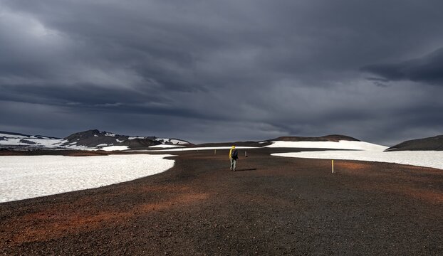 Hikers in snow-covered volcanic landscape with volcanic sand and petrified lava, crater of Askja volcano, Icelandic highlands, Iceland
