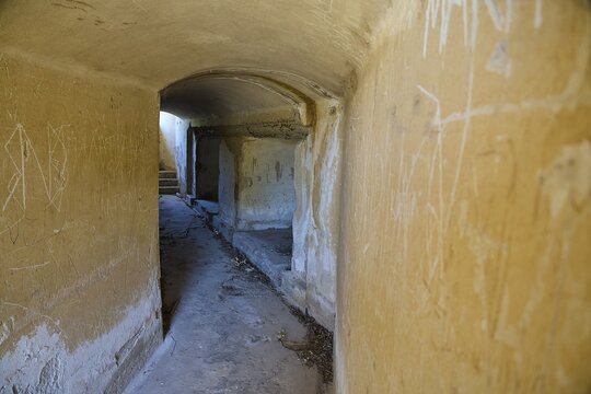 Long corridor with weathered walls leading into the darkness, mysterious and abandoned, Italian anti-aircraft position, ground defence position, PL306 with 6 cannons, WW2, Vigla Mountain, Vigla, above Lakki, Lakki, Leros, Dodecanese, Girechian Islands, Greece