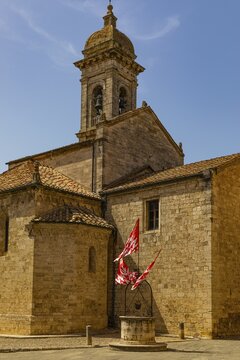 Red and white flags at the Romanesque Collegiate Church, San Quirico dOrcia, Tuscany, Italy