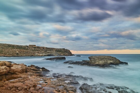 Evening light, long exposure, blurred surf, blurred clouds, bay, rocks in the sea, Mare Morto, Lampedusa Island, Agrigento Province, Pelagic Islands, Sicily, Italy
