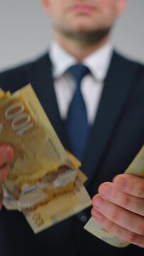 Formally dressed man is counting Canadian Dollar bills, close-up.
