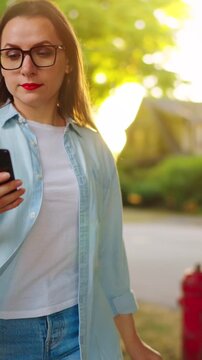 Woman using smartphone outdoors in sunny summer day. Slow motion